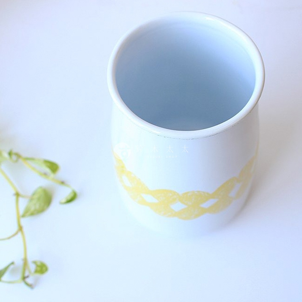 白色琺瑯材質的廚具收納筒，帶有黃色編織紋飾，筒身側面有品牌標誌。