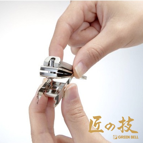 一雙手正操作著銀色金屬材質的指甲剪，指甲剪有集屑設計，細節處呈現鍛造質感。