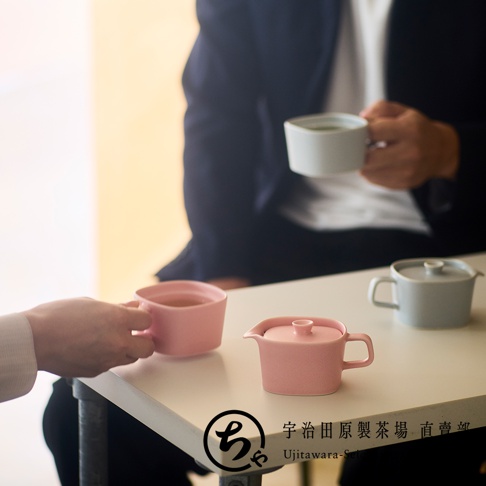 兩人在簡約風格的室內共飲，桌上擺放著宇治田原製茶場的SUKIMA系列美濃燒茶具，包含粉色與淺灰色的方圓型馬克杯與茶壺，設計現代且溫潤，呈現輕鬆愉悅的茶敘時光。