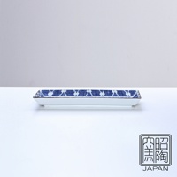 長條形白色陶瓷烤物盤，盤緣飾有藍色菱形網紋，盤邊緣有金色線條點綴，盤底有「照燒 陶瓷 JAPAN」方形黑白印章。