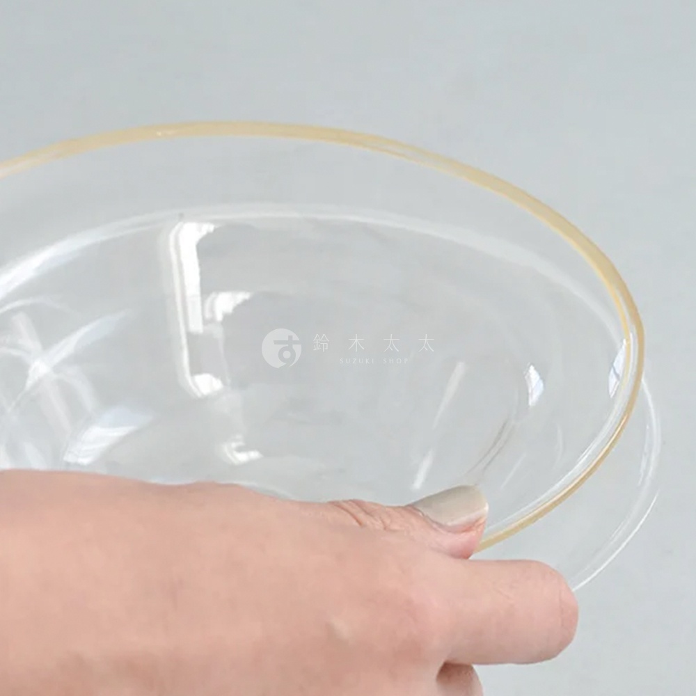 lykke 清透玻璃深型點心碗 M，由透明玻璃製成，碗口邊緣帶有金色裝飾，手部正在拿起碗。