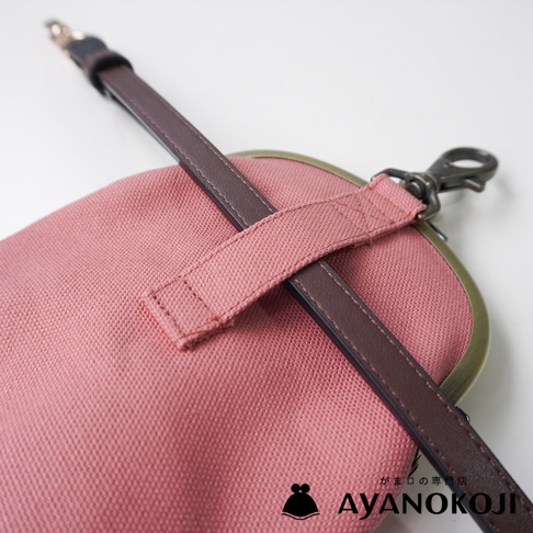 AYANOKOJI 品牌京都職人手作純棉帆布腰掛口金包，特寫鏡頭展示桃粉色帆布包的側邊，搭配咖啡色皮革帶及織帶，上方有金屬扣環。