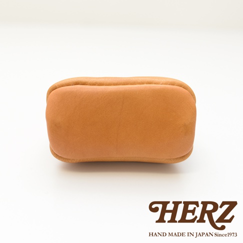 職人手作皮革口金化妝包 KF-143 S，採用柔軟的駝色皮革製成，圓潤的包身設計，展現簡約質樸的風格。