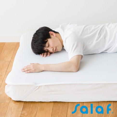 男性仰臥在白色單人睡墊上，睡墊表面有細小的菱形紋理，邊緣有鬆緊帶。