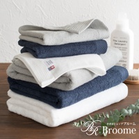 疊放的今治純棉長毛巾，有白色、淺灰色和深藍色。其中一條白色毛巾有菱紋織法和品牌標籤，顯示「towelshop broome made in japan」。