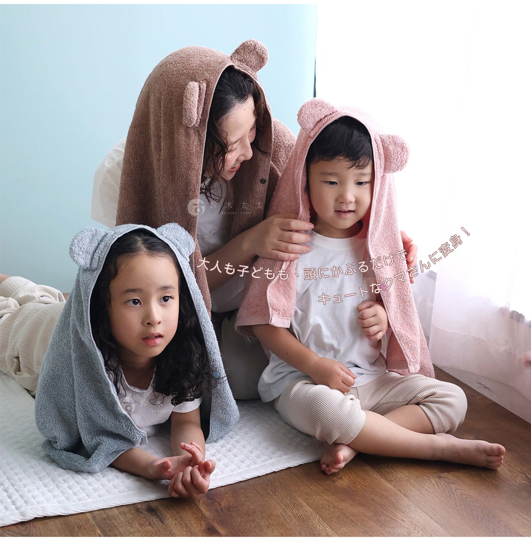 圖中可見一名女子和兩名兒童，他們都頭戴著帶有熊耳朵的粉色和棕色毛巾。左邊是一個灰藍色毛巾的女孩，中間是一個粉色毛巾的男孩，右邊是一個棕色毛巾的女子。背景是淺藍色和木質地板。
