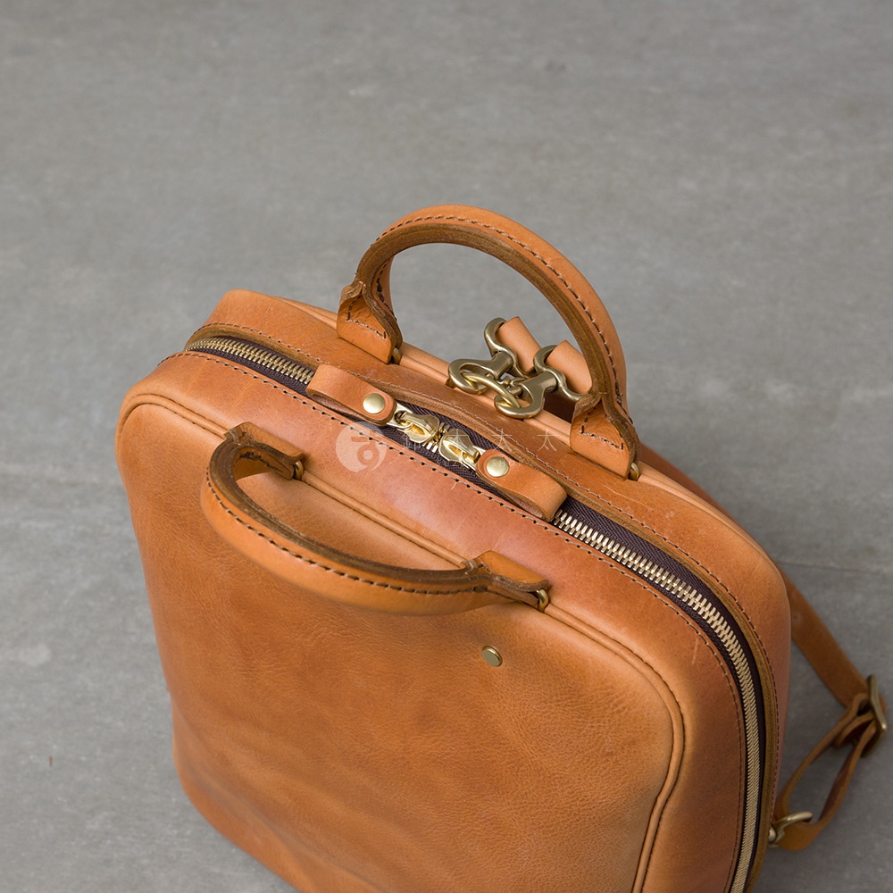 職人手作皮革Organ商務後背包，棕褐色皮革材質，配有雙提把與金色金屬拉鍊。