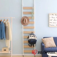 頂天立地收納掛架，白色支架搭配木紋層板，掛有棕色寬緣帽及米白色與海軍藍拼接後背包。