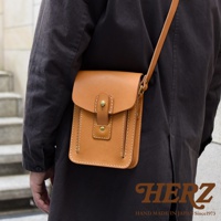 職人手作皮革休閒散步包，淺棕色，方形設計，翻蓋開合，附有金屬釦和皮製繫帶，側邊有縫線裝飾，斜背於身。