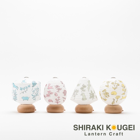 四款日式迷你裝飾提燈，紙質燈罩印有不同配色、帶有動物和植物圖案，底部為木製底座。