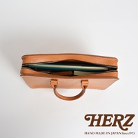 職人手作皮革公事包，淺棕色，拉鍊開口，內部可見文件夾、筆記本和錢包。