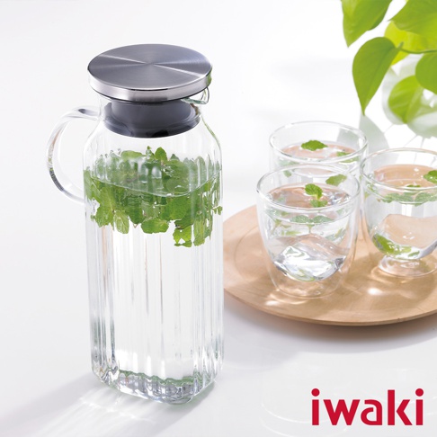 帶有不鏽鋼蓋和把手的透明玻璃方形水壺，壺內裝有水和綠色薄荷葉，旁邊擺放著三個裝有水、冰塊和薄荷葉的玻璃杯。