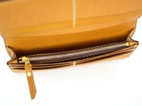 職人手作皮革長夾，呈現溫潤的咖啡色調。內裡設計有拉鍊夾層，使用金色拉鍊和同色系皮革拉頭，細節處縫線工整。