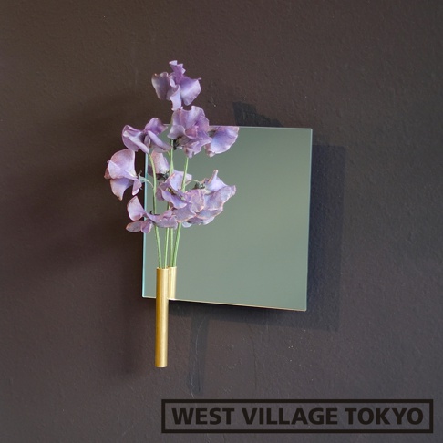 壁掛式鏡面花器，附有金色金屬單輪花瓶，展示一束紫色花朵，鏡面為淺綠色。