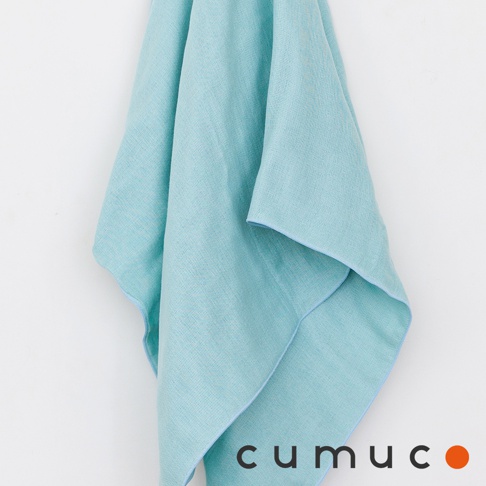 一條淺綠色的 CUMUCO 六層紗浴巾懸掛在白色背景前，布料呈現出細緻的織紋質感，邊緣縫線整齊，整體視覺簡約且具有透氣感，底部印有深色的品牌名稱與一個橘色圓點。