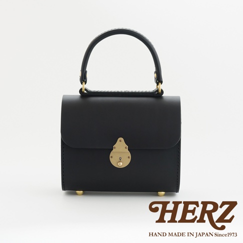 黑色皮革復古杜勒斯手提包，配有金色鎖扣和提把。包包底部有四個金色金屬腳釘。