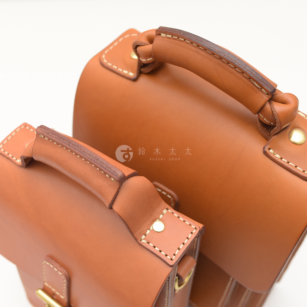 兩款淺棕色皮革小方包，特寫提把與縫線細節，材質為天然皮革，設計簡約，適合單肩斜挎。