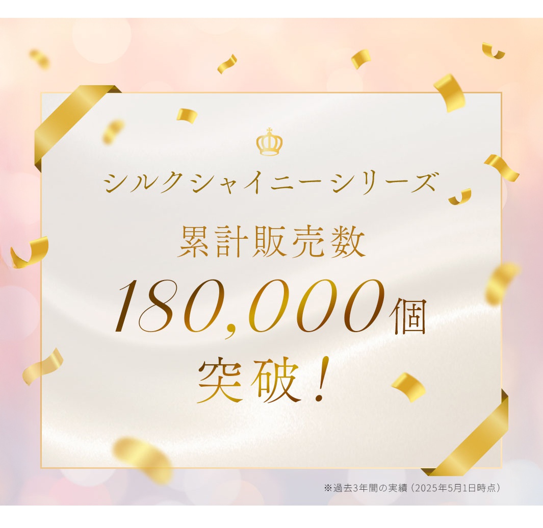 金色皇冠標誌下的白色背景，印有金色日文文字「シルクシャイニーシリーズ 累計販売数 180,000個 突破！」（絲綢閃亮系列 累計銷量突破180,000件！），四角裝飾金絲帶，背景為粉色漸層，灑落金色紙屑。