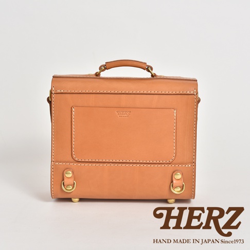 皮革學院風三用迷你後背包，呈現天然皮革的溫潤色澤，方形箱型設計，正面有品牌壓印與立體口袋，搭配金屬扣環與提把，風格簡約復古。