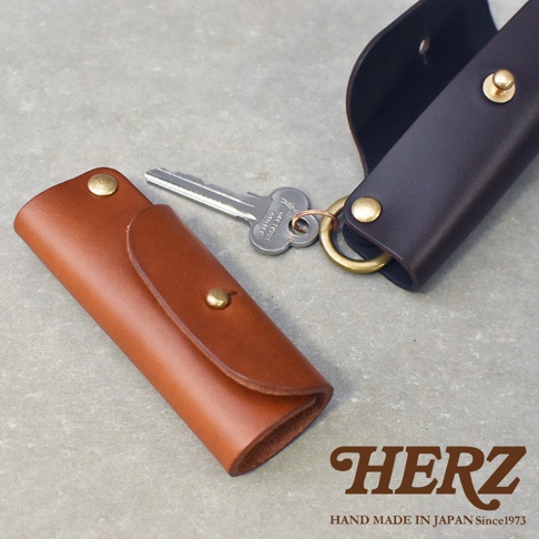 職人手作皮製鑰匙套，包含棕色與深棕色兩款，配有銀色鑰匙和黃銅扣環。