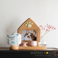 木製迷你提燈，白色紙質燈罩飾有藍色小動物與植物圖案，置於圓形木製底座上。旁邊是貓咪照片相框、粉色小碗與透明玻璃花瓶插有紅色小花。