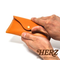 一雙手正在拿著一個橘色的皮革眼鏡盒，盒子上有一顆金屬按扣。