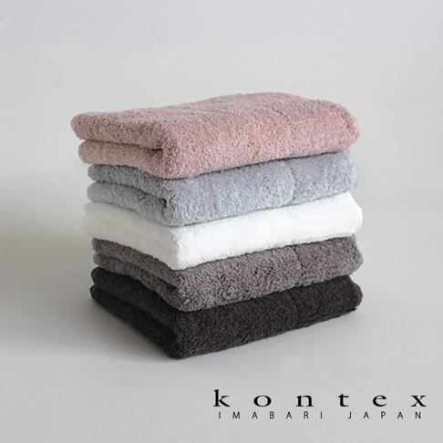 疊放著五條今治極柔蓬鬆大毛巾，顏色由上至下分別為粉紅色、淺灰色、白色、深灰色和黑色，毛巾材質看起來蓬鬆柔軟。