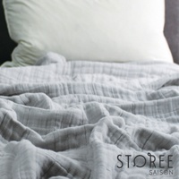 九層紗單人毯，呈現輕柔的淺灰色，布料有明顯的皺褶紋理，質地輕薄透氣。