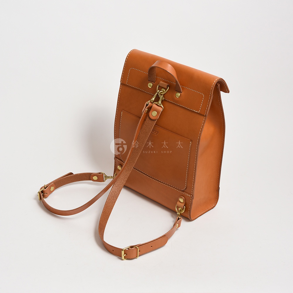 職人手作皮革紙袋風後背包，以棕色皮革製成，設計簡約，帶有可調節的肩帶和金屬扣環。