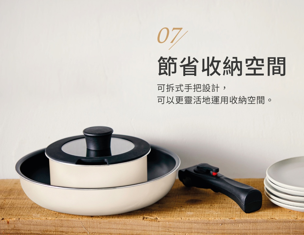 曜石黑鑽石塗層IH不沾鍋具4件組，包含一個米白色鍋子、一個黑色鍋蓋，以及一個可拆卸的黑色鍋柄，旁邊堆疊著幾個白色盤子。