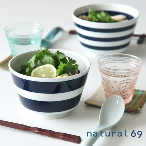 海軍風條紋丼碗，有深藍色與白色寬條紋，陶瓷材質。碗內盛有香菜、檸檬片及其他食材。前景有湯匙和筷子，背景另有一碗條紋丼碗和兩杯飲料。