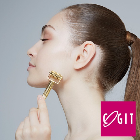 COGIT 品牌標誌置於圖片右下角，一女子側臉，手持金色滾輪式美顏儀，正於臉頰上按摩。