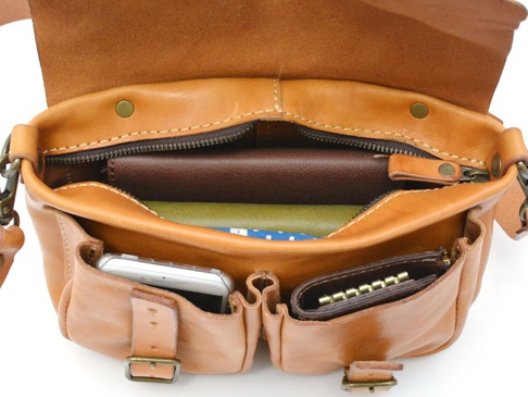 職人手作皮革水洗加工前雙口袋肩背包，呈現自然棕褐色，包身結構完整，內部包含手機、皮夾、筆記本等物品，並有拉鍊隔層。