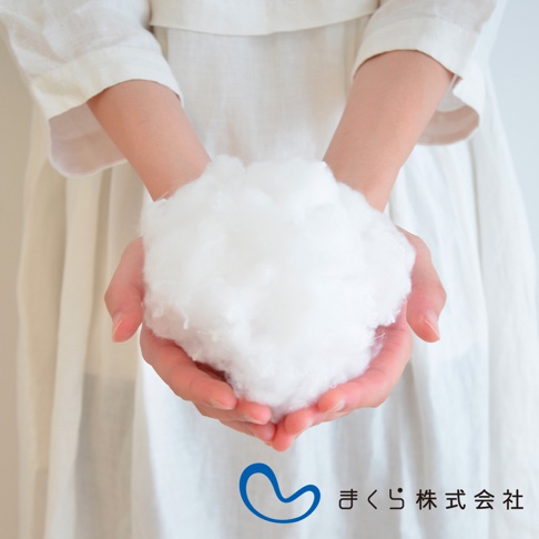 雙手捧著蓬鬆、柔軟的白色填充物，展示枕頭的填充材質，背景為穿著白色衣物的女性。