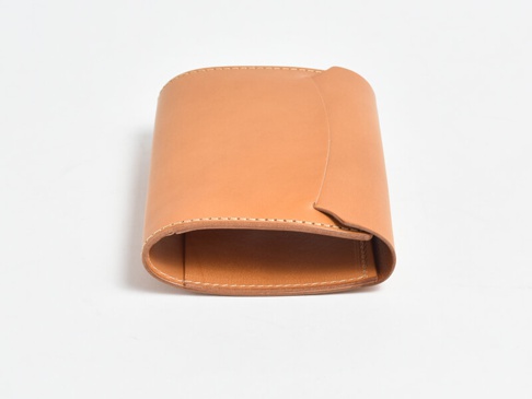 淺棕色皮革製成的 A6 記事本書套，帶有手工縫線細節，設計簡潔，頂部邊緣有獨特的翻折造型。