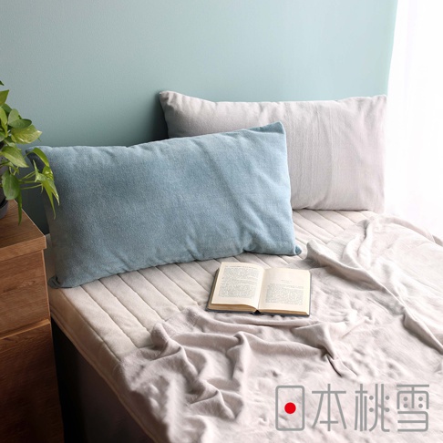 藍色和淺灰色的吸濕透氣絲絨風毛巾枕套，柔軟親膚，搭配床舖和一本打開的書，營造舒適家居氛圍。