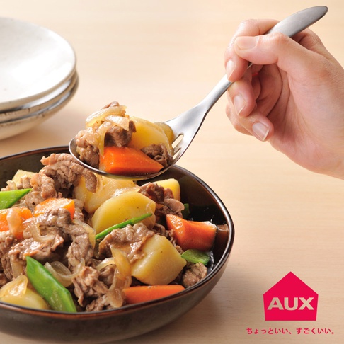 一只手拿著不鏽鋼濾水菜匙，匙中盛著燉牛肉、馬鈴薯、紅蘿蔔和荷蘭豆，菜匙有兩個濾水孔。