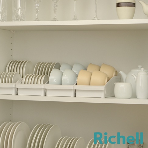櫥櫃架上整齊擺放著白色和淺藍色的盤子、淺黃色的杯子，以及白色茶壺組。