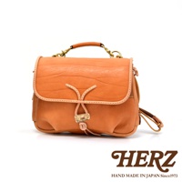 手工製作的棕褐色皮革郵差包，帶有鹿角扣和抽繩設計，搭配金屬扣環和可拆卸提把。