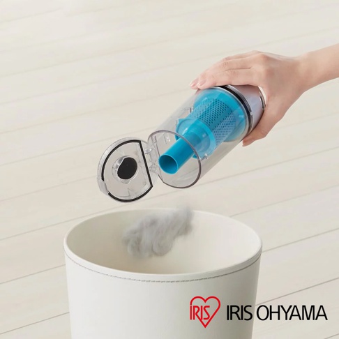 手持吸塵器集塵筒，內含藍色濾網，正將灰色灰塵倒入白色垃圾桶。