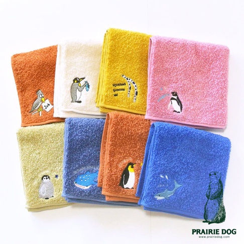 展示一系列色彩鮮豔的今治精梳棉方巾，包含橘色、米白色、黃色、粉紅色、淺綠色和藍色。每條方巾上都有可愛的動物刺繡，如企鵝、鳥、鯨鯊和海豚。