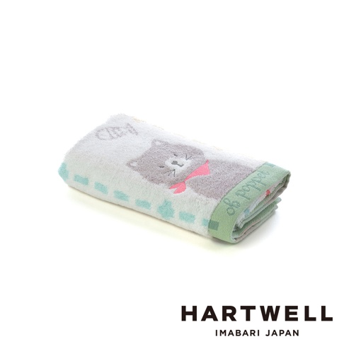 一條摺疊好的Hartwell今治森林動物系列毛巾，正面有可愛的灰色貓咪圖案並繫著粉色蝴蝶結，邊緣裝飾著淺綠色條紋與Hartwell的英文草寫字樣，背景為純白，整體呈現出溫柔舒適的質感。