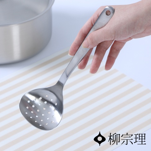 一只手正拿著一個不鏽鋼圓孔杓，杓面有許多圓形小孔，杓柄末端有個掛孔。
