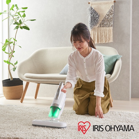 一位女性使用銀色無線吸塵器清潔白色地毯，吸塵器具有透明綠色集塵筒。