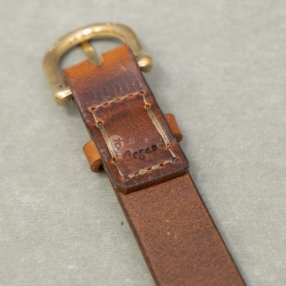 日本HERZ Organ職人手作皮革皮帶，近拍一金屬釦與棕色皮革。