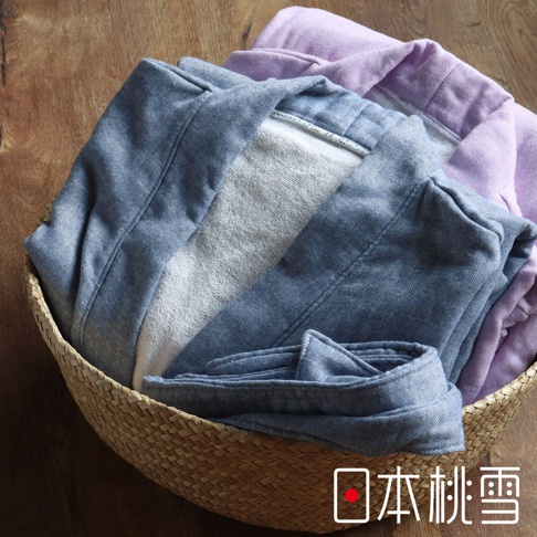 藤編籃中疊放著三件異材質的浴袍：一件淺藍色牛仔布料、一件淺灰色毛巾布料、一件淺紫色布料，皆為浴袍款式。