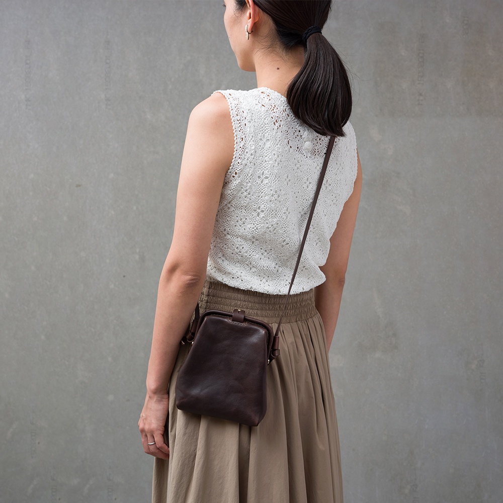 職人手作皮革Organ迷你杜勒斯側背包，深棕色，翻蓋設計，搭配細長肩帶，斜挎於身。