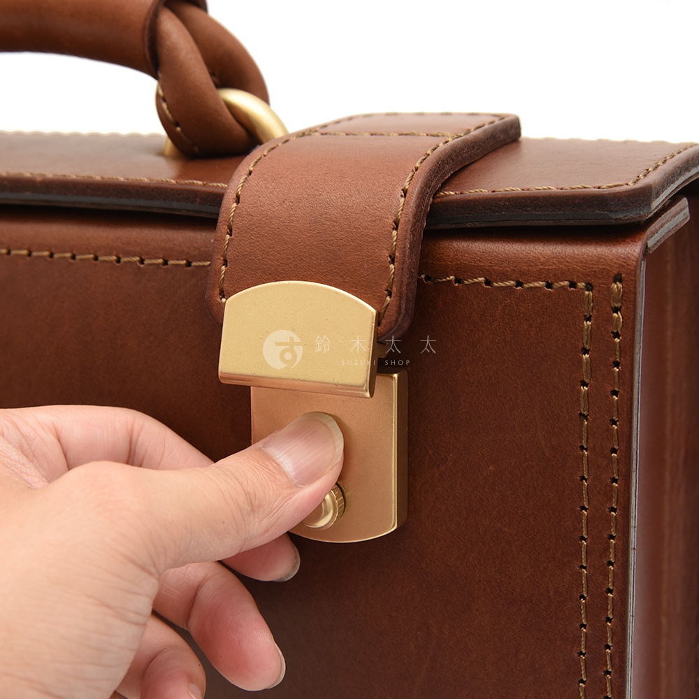 職人手作皮革兩用機師箱，深棕色皮革，配有黃銅色金屬鎖扣和提把。箱體邊緣有縫線裝飾，展現細緻工藝。