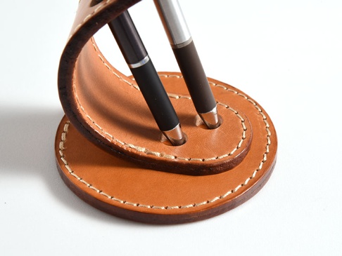 職人手作皮革兩入用筆架，淺棕色皮革，搭配米白色縫線，可容納兩支筆，設計簡約。