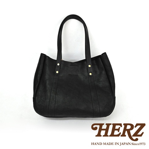 黑色皮革仕女托特包，雙提把設計，包身有縫線裝飾，兩個金色鉚釘固定提把，簡約大方。